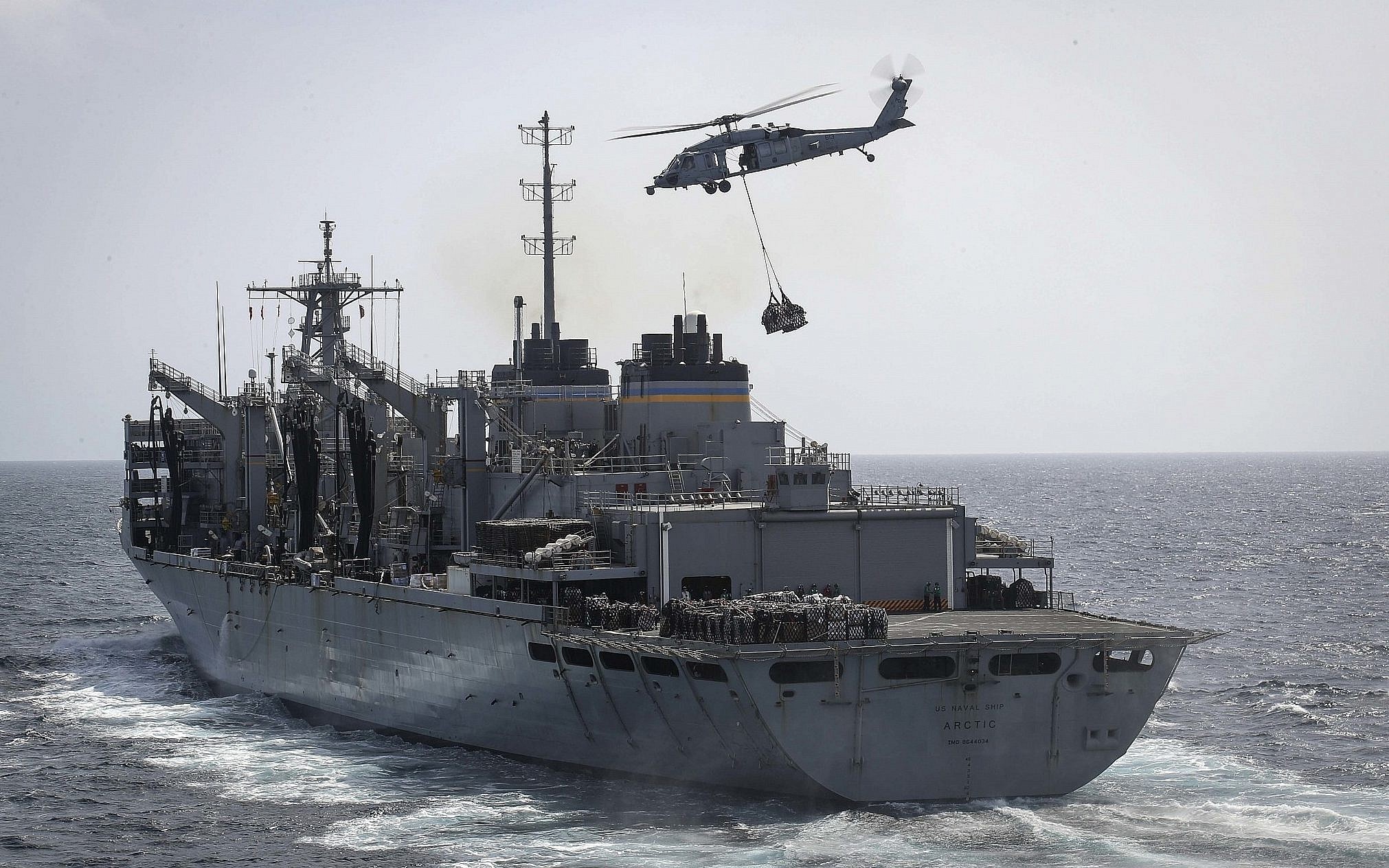 An MH-60S Sea Hawk helicopter transports cargo from the fast combat support ship USNS Arctic to the Nimitz-class aircraft carrier USS Abraham Lincoln during a replenishment-at-sea in the Arabian Sea (AP)