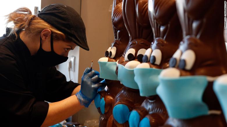 A cake shop employee in Athens Greece prepares chocolate Easter bunnies with face masks April 8 (Getty)