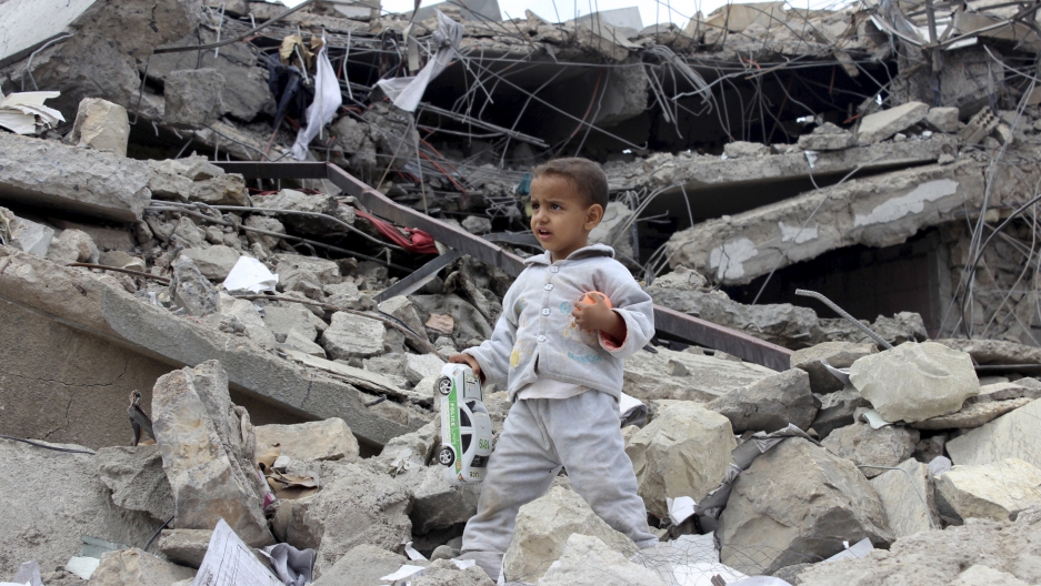 A boy walks as he collects toys from the rubble of a house destroyed by a recent air strike in Yemen's north-western city of Saada [Reuters]