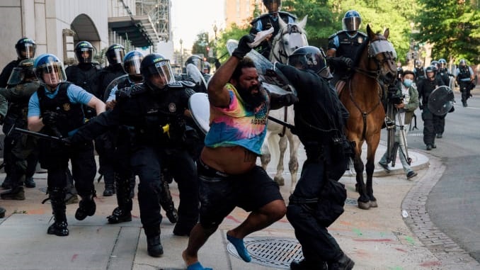 Riot police chase a man as they rush protestors to clear Lafayette Park across from the White House (Reuters)